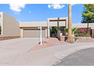 Front view of a tan house with a gated entry and brick walkway at 9025 N 86Th Pl, Scottsdale, AZ 85258