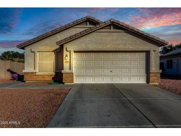 One-story house with light beige exterior, a two-car garage, and rock landscaping at 12962 W Catalina Dr, Avondale, AZ 85392