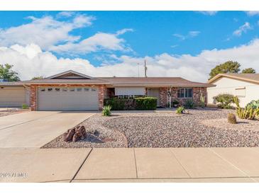 Brick ranch house with landscaped yard, two-car garage, and driveway at 910 S Portland Cir, Mesa, AZ 85206