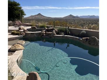 Inviting pool with mountain views and a rock waterfall feature at 9697 E Preserve Way, Scottsdale, AZ 85262