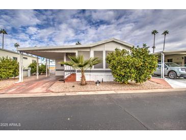 Single-wide manufactured home with carport and nicely landscaped front yard at 7750 E Broadway Rd # 674, Mesa, AZ 85208