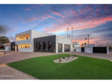 Modern two-story home with a sleek design, landscaped lawn, and gated entry at 9809 E Desert Cove Ave, Scottsdale, AZ 85260