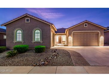 Tan colored house with a two-car garage and nicely landscaped front at 24018 N 165Th Dr, Surprise, AZ 85387