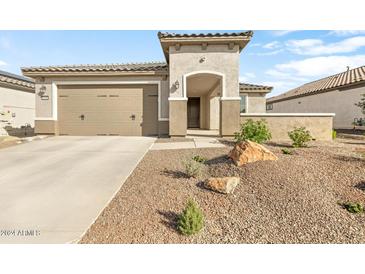 Tan colored house with a two-car garage and drought tolerant landscaping at 26448 W Kimberly Way, Buckeye, AZ 85396