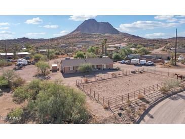 Aerial view of a ranch-style home with a corral, mountain backdrop, and ample parking at 47435 N Meander Rd, New River, AZ 85087