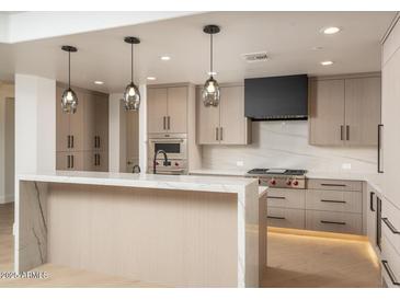 Modern kitchen with island, stainless steel appliances, and light wood cabinets at 7175 E Camelback Rd # 601, Scottsdale, AZ 85251