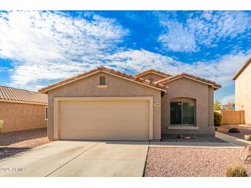 Tan house with a two-car garage and desert landscaping at 7244 S Sunrise Way, Buckeye, AZ 85326