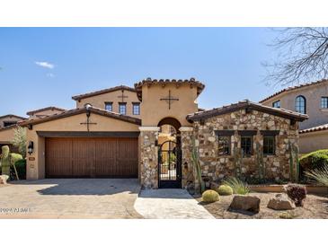 Inviting exterior with stone accents and a large wooden garage door at 19627 N 101St St, Scottsdale, AZ 85255