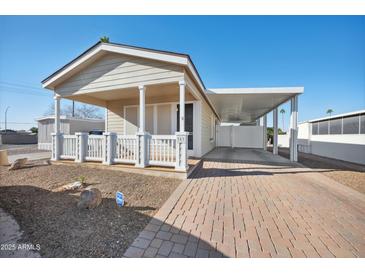 Tan single-story home with covered porch, carport, and well-maintained landscaping at 201 S Greenfield Rd # 353, Mesa, AZ 85206