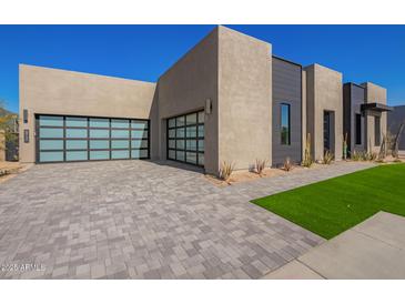 Modern home exterior with a three-car garage and landscaped front yard at 5740 E Moura Dr, Cave Creek, AZ 85331