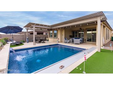 Inviting backyard pool with a covered patio and putting green at 17937 W Cedarwood Ln, Goodyear, AZ 85338