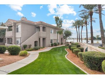 Exterior view of condo building with lush landscaping and a pathway leading to a waterfront at 3830 E Lakewood Pkwy # 1166, Phoenix, AZ 85048