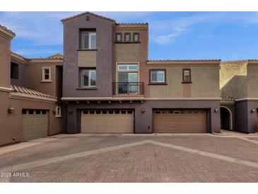 Three-story townhome with attached two-car garage and Spanish-style architecture at 3935 E Rough Rider Rd # 1076, Phoenix, AZ 85050