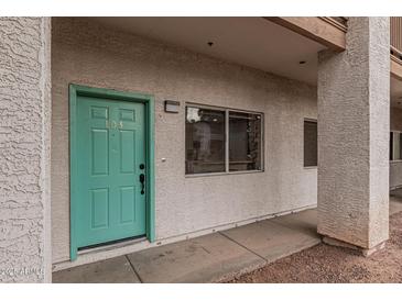 Exterior view of condo building showcasing teal door and walkway at 6920 E 4Th St # 103, Scottsdale, AZ 85251