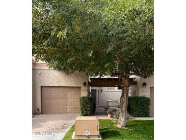 Tan stucco condo exterior with two-car garage, covered entryway, and mature landscaping at 9705 E Mountain View Rd # 1056, Scottsdale, AZ 85258