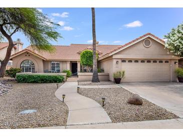 Single-story home with a landscaped front yard and two-car garage at 10043 E Dreyfus Ave, Scottsdale, AZ 85260