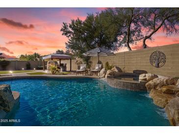 Inviting backyard oasis with a sparkling pool, spa, and relaxing seating area at 40208 N Faith Ln, Anthem, AZ 85086