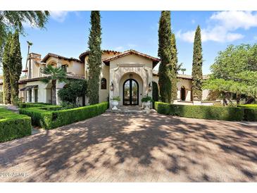 Stately home with a circular brick driveway, manicured hedges, and an arched entryway with black iron doors at 6800 E Caballo Dr, Paradise Valley, AZ 85253
