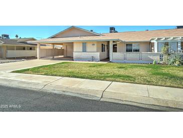 Ranch-style home with carport and well-manicured lawn at 10252 N 105Th Dr, Sun City, AZ 85351