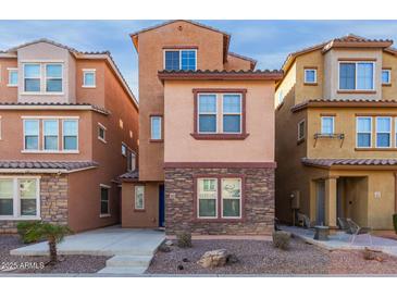 Three-story townhome with stone accents and a front patio at 2028 N 77Th Ln, Phoenix, AZ 85035