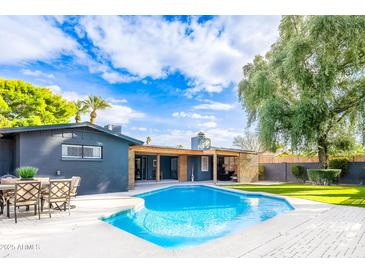 Inviting backyard featuring a sparkling pool, lush greenery, and covered patio area, perfect for outdoor entertaining at 2942 N 81St Pl, Scottsdale, AZ 85251