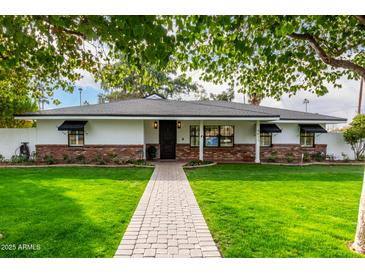 Beautiful ranch home with brick accents, lush lawn, and a paved walkway at 4017 E Wilshire Dr, Phoenix, AZ 85008