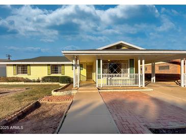 Charming yellow house with a covered porch and well-maintained landscaping at 5708 W Belmont Ave, Glendale, AZ 85301