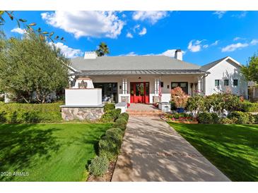 White brick home with red door, covered porch, and landscaped yard at 6602 E Lafayette Blvd, Scottsdale, AZ 85251