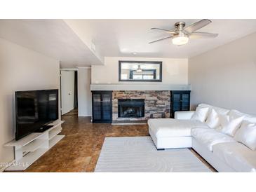 Living room features a stone fireplace, white sectional sofa, and tile flooring at 850 S River Dr # 1066, Tempe, AZ 85281