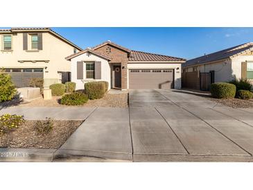 Single-story home with brown garage door, light-colored walls, and landscaping at 25151 N 143Rd Dr, Surprise, AZ 85387