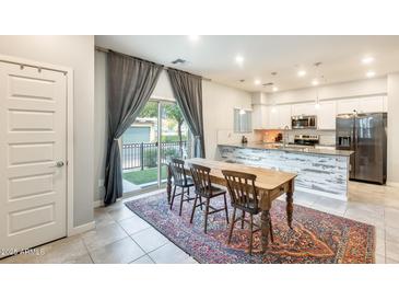 Modern kitchen with white cabinets, stainless steel appliances, and a farmhouse table at 2722 S Cavalier Dr # 102, Gilbert, AZ 85295