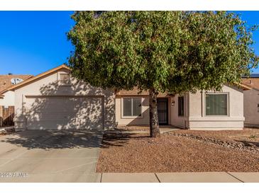 Single-story home with two-car garage and mature tree in front yard at 14352 W Lamoille Dr, Surprise, AZ 85374