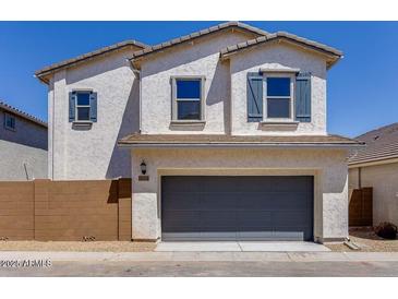 Two-story home featuring stucco siding, blue shutters, and a two-car garage under a bright blue sky at 14644 W Sand Hills Rd, Surprise, AZ 85387