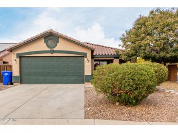 Tan house with a green garage door and landscaped front yard at 15720 W Crocus Dr, Surprise, AZ 85379