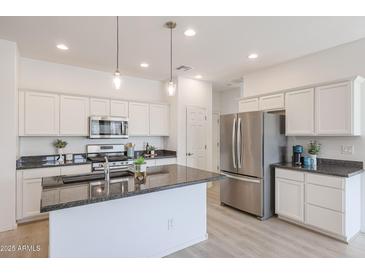 Modern kitchen with white cabinets, granite countertops, and stainless steel appliances at 18171 W Glenhaven Dr, Goodyear, AZ 85338