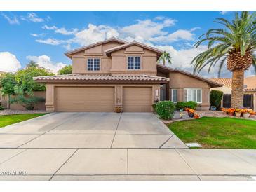 Two-story house with a three-car garage and landscaped front yard at 4043 W Saguaro Park Ln, Glendale, AZ 85310