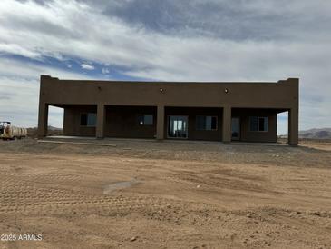 Single story home with a flat roof and desert landscape and covered porch, displaying its architectural style at 48548 W Long Rifle Rd, Aguila, AZ 85320