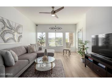 Bright living room with L-shaped sofa, large TV, and wood-look floors at 5350 E Deer Valley Dr # 2403, Phoenix, AZ 85054