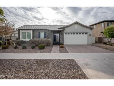 One-story home with gray brick, white garage door, and landscaped front yard at 10053 E Seismic Ave, Mesa, AZ 85212