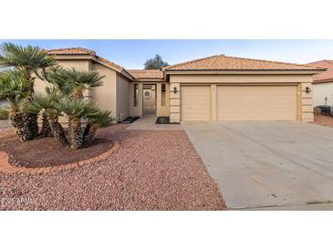 Tan two-car garage home with desert landscaping and a walkway at 10828 E Flintlock Dr, Sun Lakes, AZ 85248