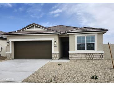 Charming single-story home featuring a two-car garage and neutral-toned stucco with brick accents at 1587 S 239Th Dr, Buckeye, AZ 85326