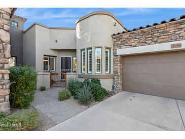 Inviting stucco and stone exterior, two-car garage, and landscaped front yard at 19550 N Grayhawk Dr # 1136, Scottsdale, AZ 85255