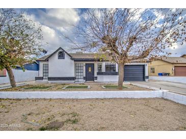 Cute single story home with a landscaped front yard and black garage door at 6145 W Pierce St, Phoenix, AZ 85043