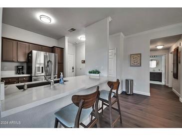 Modern kitchen with stainless steel appliances, breakfast bar, and dark cabinets with light countertops at 7009 E Acoma Dr # 1004, Scottsdale, AZ 85254