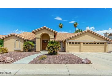 Tan two-story house with tile roof, three-car garage, and desert landscaping at 7146 W Emile Zola Ave, Peoria, AZ 85381