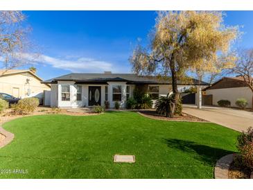 White house with a black door, green lawn, and driveway at 19819 N 6Th Dr, Phoenix, AZ 85027