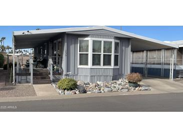 Gray manufactured home with covered porch, landscaping, and a paved driveway at 205 S Higley Rd # 299, Mesa, AZ 85206