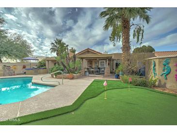 Spacious backyard oasis with a sparkling pool, putting green, and covered patio at 2131 W Ironwood Dr, Chandler, AZ 85224