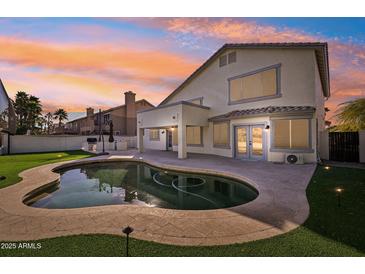 Stunning backyard oasis with a kidney-shaped pool, outdoor kitchen, and landscape lighting at 6270 W Rose Garden Ln, Glendale, AZ 85308