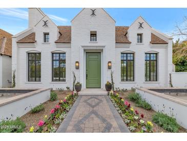 Stunning white brick home with a green door, landscaped walkway, and flowerbeds at 6737 E Exeter Blvd, Scottsdale, AZ 85251